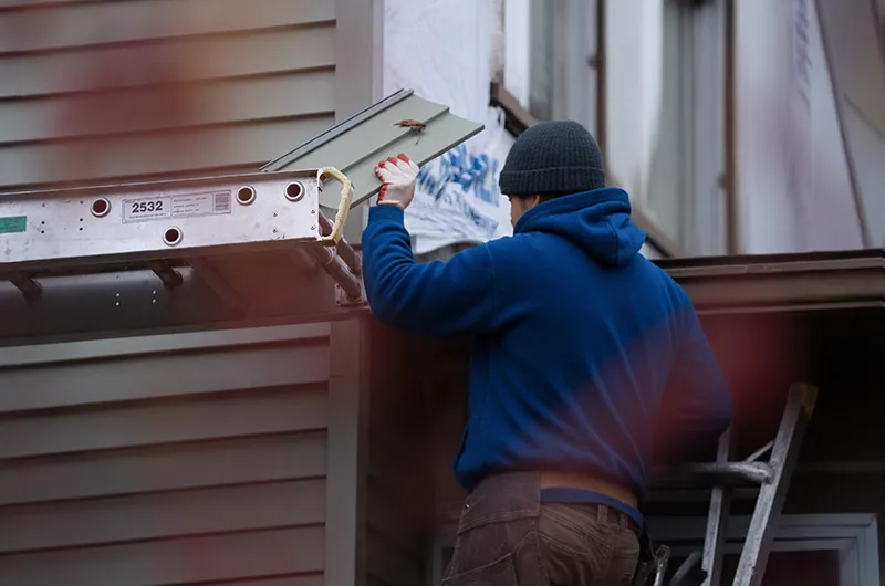 man installing siding on a house